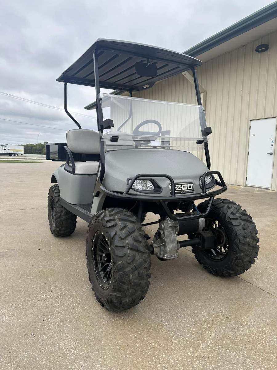 Off-road golf cart with rugged tires and canopy parked outside.