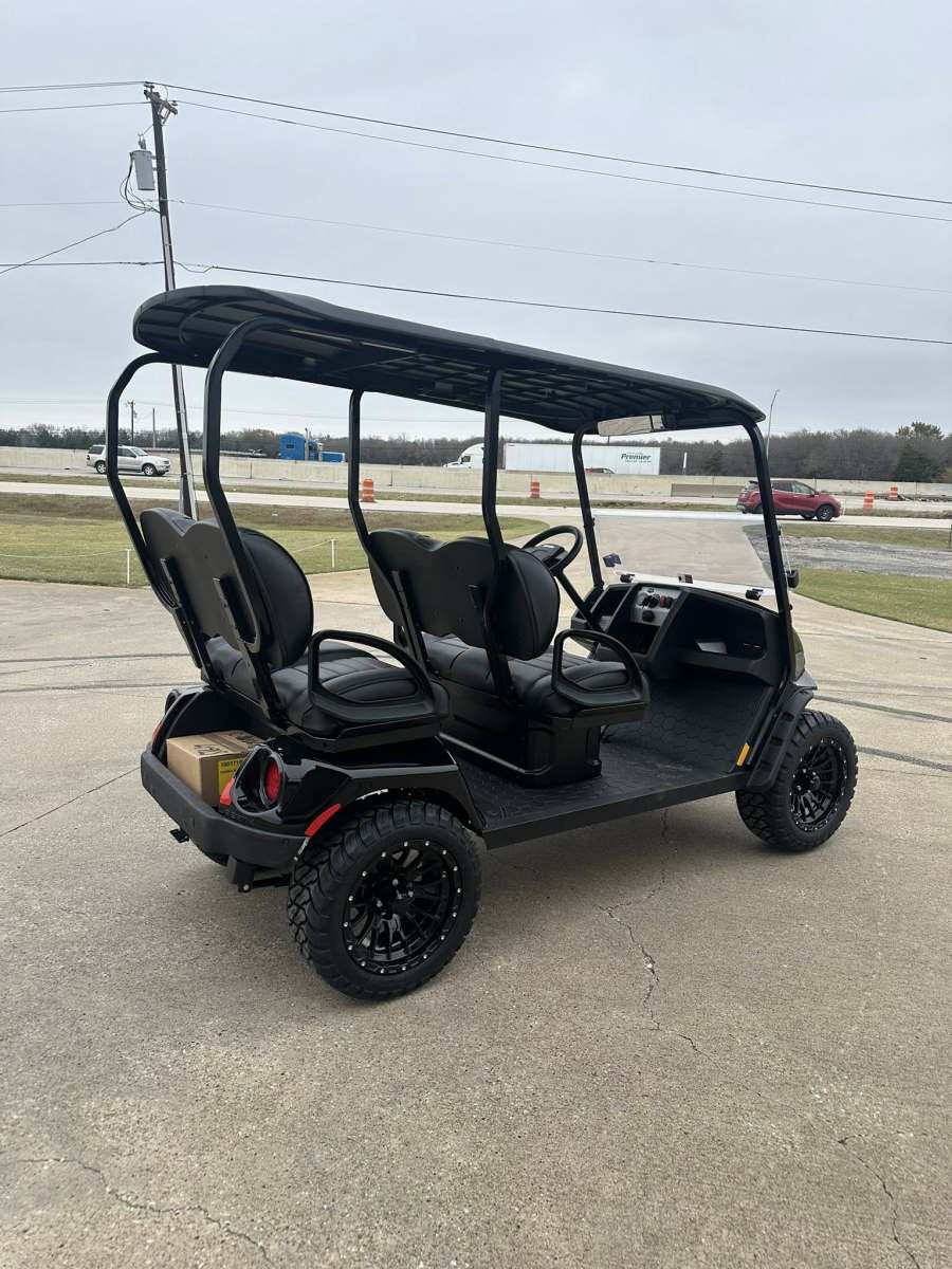 Black golf cart with four seats parked on pavement.